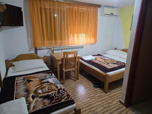 a room with two beds and a table and a chair at Vila PAUN in Doboj