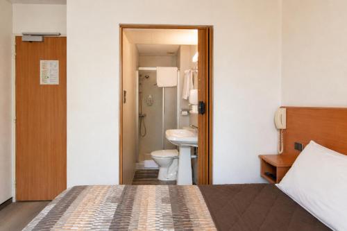 a bathroom with a bed and a sink and a toilet at Hôtel Compostelle in Lourdes