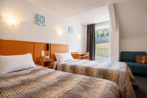 a hotel room with two beds and a window at Hôtel Compostelle in Lourdes