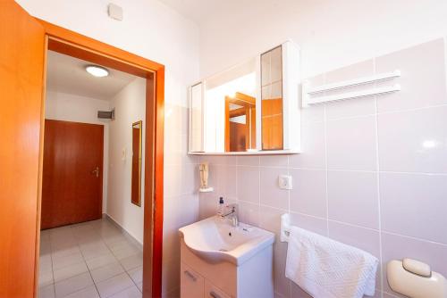 a white bathroom with a sink and a mirror at Apartments Silvia in Novalja