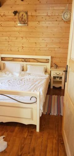 a bedroom with a white bed and a wooden wall at Casuta lui Andrei in Brezoi