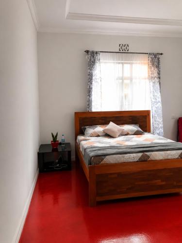 a bedroom with a bed with a red floor and a window at Jules Place Arusha in Themi