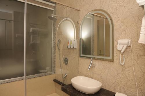 a bathroom with a shower and a sink and a mirror at Hotel Sachin in Chas