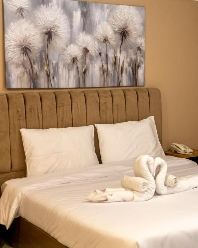 a bed with white towels on it with a painting at فندق جراند السالمية Salmiya Grand Hotel in Kuwait