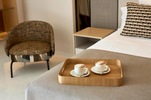 a tray with two cups of coffee on a bed at Insotel Fenicia Prestige Suites & Spa in Santa Eularia des Riu