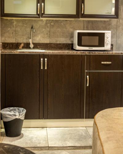 a kitchen with brown cabinets and a microwave at فندق جراند السالمية Salmiya Grand Hotel in Kuwait
