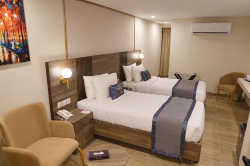 a hotel room with two beds and a chair at RT Serene Hotel - Hyderabad in Hyderabad