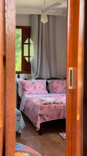 a bedroom with a bed with pink sheets and a window at Casa Ferrari in Santa Teresa