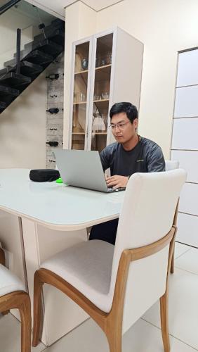 a man sitting at a table with a laptop at Suite Vila dos Cabanos Barcarena in Barcarena