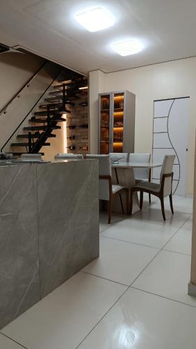 a dining room with a table and a staircase at Suite Vila dos Cabanos Barcarena in Barcarena
