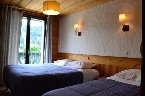 two beds in a hotel room with a window at Chalet Fleur des Alpes 1 in Les Gets