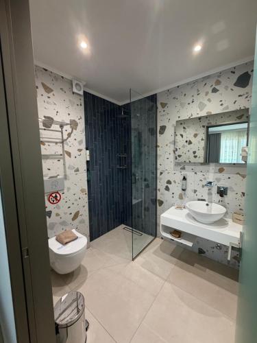 a bathroom with a toilet and a sink at Elegant Corner Superior Rooms & Apartments in Limenaria