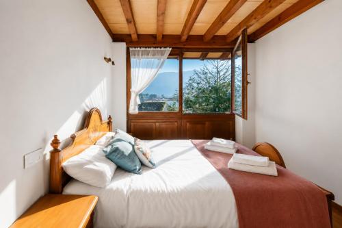 a bedroom with a large bed with a window at Llanes Casa cerca Playa y Centro – Encina Pancar in Pancar
