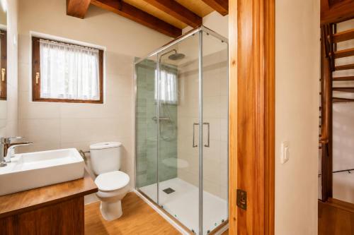a bathroom with a toilet and a glass shower at Llanes Casa cerca Playa y Centro – Encina Pancar in Pancar