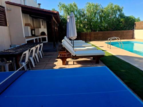 a group of chairs and an umbrella next to a swimming pool at Villa Thalasena in episkopi-heraklion