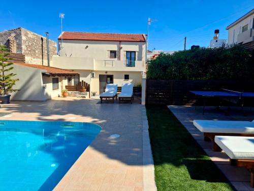 a backyard with a swimming pool and a house at Villa Thalasena in episkopi-heraklion