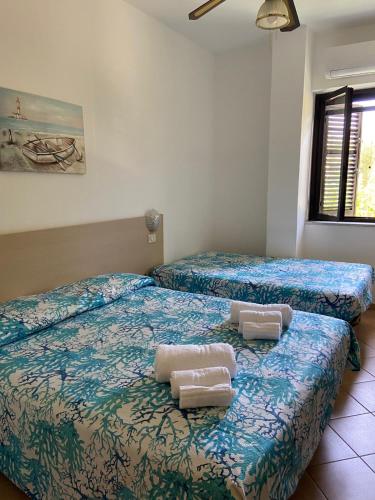 a bedroom with two beds with towels on them at Cardiff Hotel in Marina di Camerota