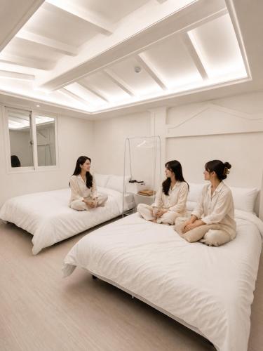 three women sitting on beds in a room at Olli Haus in Seoul