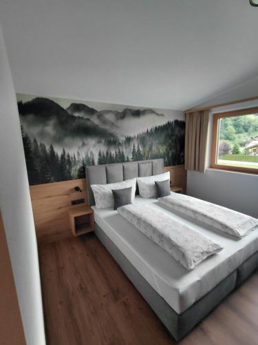 a bedroom with a large bed with a painting on the wall at Appartement Schroll in Schwendau