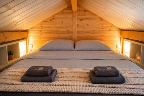 a bed in a wooden room with two towels on it at NicePlace4You Familien-Ferienhäuser an der polnischen Ostsee mit Pool in Dobiesławiec