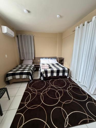 two beds in a room with a large rug at Refugio Centrico in Ciudad del Este