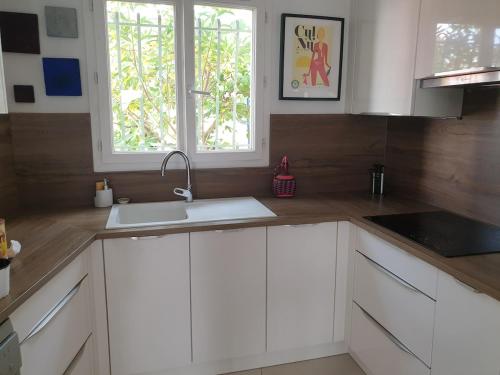 a kitchen with white cabinets and a sink and a window at Maison MATIASMA avec Jacuzzi in Hyères