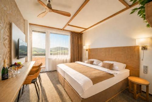 a hotel room with a bed and a desk and a window at Hotel Adamantino in Luhačovice