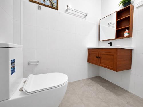 a white bathroom with a toilet and a mirror at The Beach House , Nilaveli , Trincomalee in Trincomalee