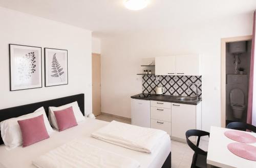 a white room with a bed and a kitchen at Apartment Šušanj in Karlobag