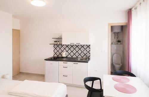 a kitchen with white cabinets and a table and chairs at Apartment Šušanj in Karlobag