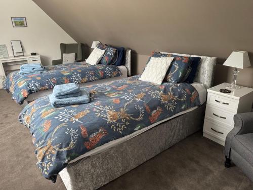 a bedroom with two beds and a dresser with a night stand at Woodlands Banff in Banff