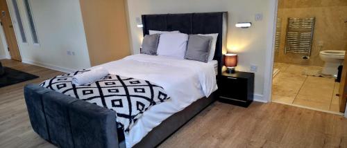 a bedroom with a large bed and a bathroom at West Beck House Darlington - Penthouse Double En-Suite in Darlington