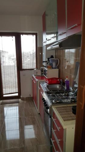cocina con armarios rojos y fogones en Apartment Mamaia Nord, en Mamaia Nord – Năvodari
