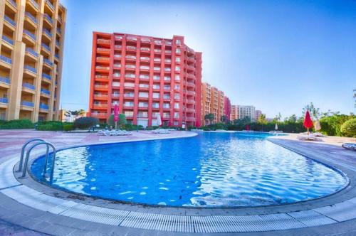 a large swimming pool in front of a tall building at Amer group in El Alamein