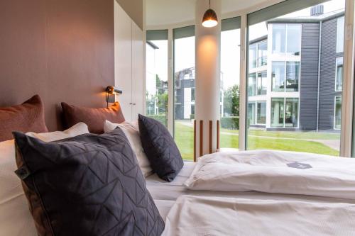 a bedroom with a bed with pillows and a large window at Kolding Hotel Apartments in Kolding
