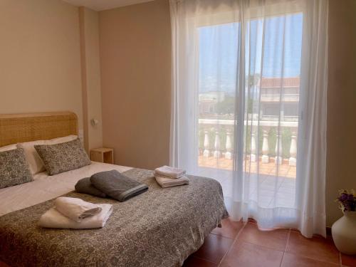 a bedroom with a bed and a large window at Duna Blanca House - Piscina privada - 450m de la playa in Daimuz