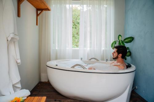 a man sitting in a bath tub in a bathroom at Matiz Igaratá Resort, Spa e Eventos in Igaratá