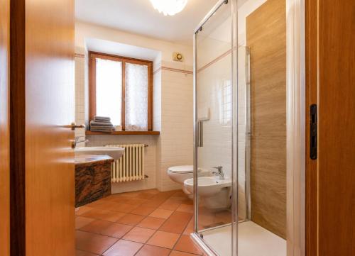 a bathroom with a toilet and a glass shower at Appartamento Brione Lido in Nago-Torbole