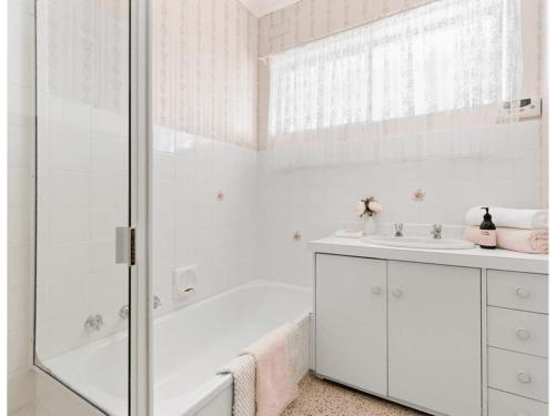 a white bathroom with a tub and a sink at Spacious and Modern Guest House in Gilles Plains
