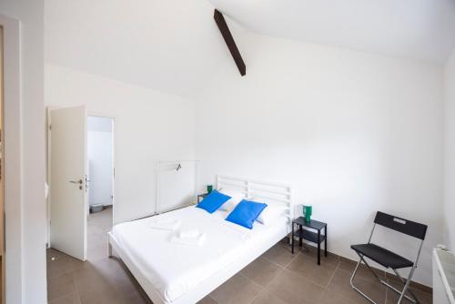 a white bed with blue pillows in a room at Triple Evasion Terrasse in Zillisheim