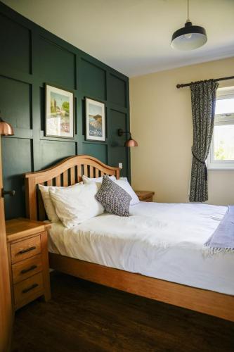 a bedroom with a white bed with green walls at Ger Yr Afon in Saint Harmon