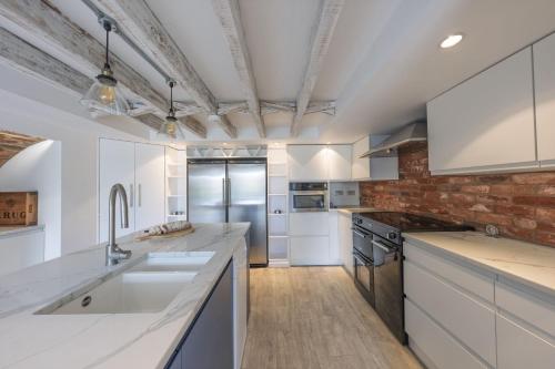 a kitchen with white cabinets and a brick wall at Watch Cottage in Lymington
