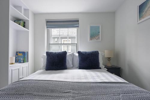 a bedroom with a bed with blue pillows and a window at Watch Cottage in Lymington