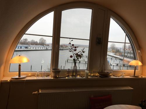 a window with two lamps and a view of a harbor at Hafenidyll mit Wasserblick in Karlshagen