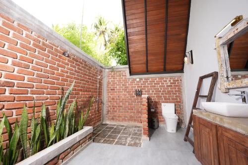 a bathroom with a sink and a brick wall at Aalanga Escape in Kanugala
