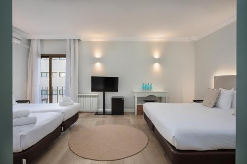 a hotel room with two beds and a television at Hotel Montjoi by Brava Hoteles in Sant Feliu de Guíxols