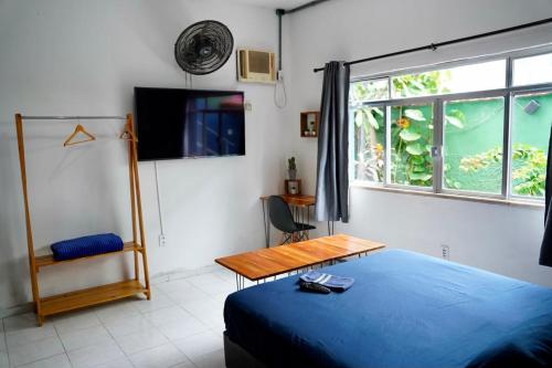 a bedroom with a bed and a table and a tv at La Casa Hostel in Arraial do Cabo