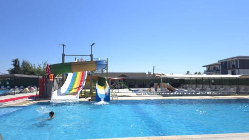 two people in a swimming pool with a water slide at AQUA MARMARA LİFE Hotel in Marmaraereglisi