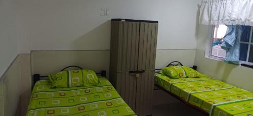 two beds in a room with green sheets and a window at Casa SAYBER DON DIEGO in Don Diego