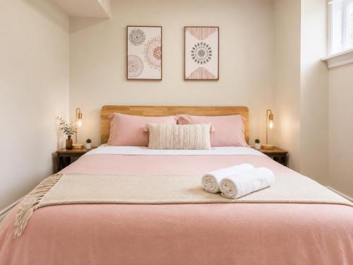 a bedroom with a pink bed with two towels on it at Chic & Spacious 2BR Home Near Yonge St in Newmarket